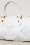 White leather handbag with embossed Louis Vuitton monogram pattern and gold-tone hardware, shown in a close-up studio-style shot.