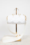 A white Louis Vuitton Speedy handbag with embossed monogram pattern and gold-tone hardware, displayed on a gold stand with a matching white shoulder strap on a marble surface against a white background.
