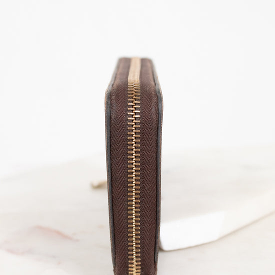 Brown leather wallet with gold zipper on a white background