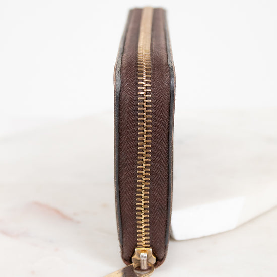 Brown wallet with gold zipper on a white background