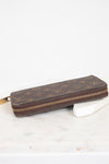 Brown wallet with gold zipper on a white marble surface