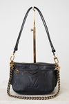 A black Louis Vuitton monogram shoulder bag with gold-tone hardware and a gold chain strap, displayed on a white background with a gold stand.
