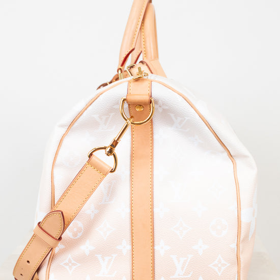 Designer handbag with beige strap and white monogram pattern on a light gray background