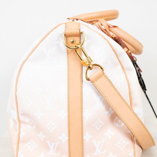 Side view of beige duffle bag with tan leather trim on white background