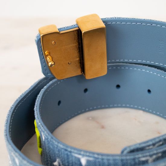 Close-up of a blue denim belt with a brown buckle on a light background