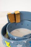 Close-up of a blue denim belt with a brown buckle on a light background