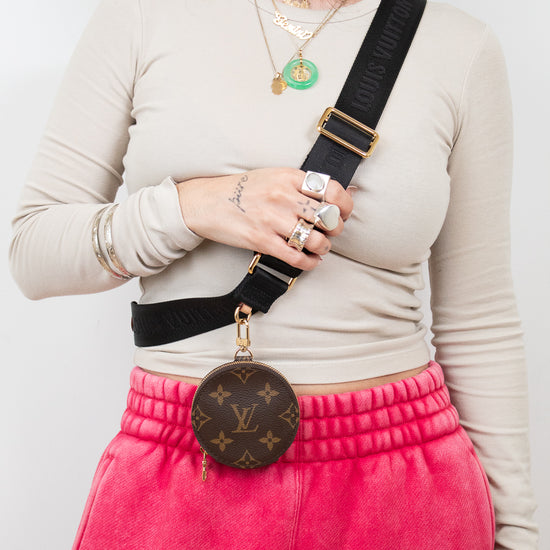 Person wearing a beige long-sleeve top, pink sweatpants with 'Wang' branding, and carrying a Louis Vuitton bag.