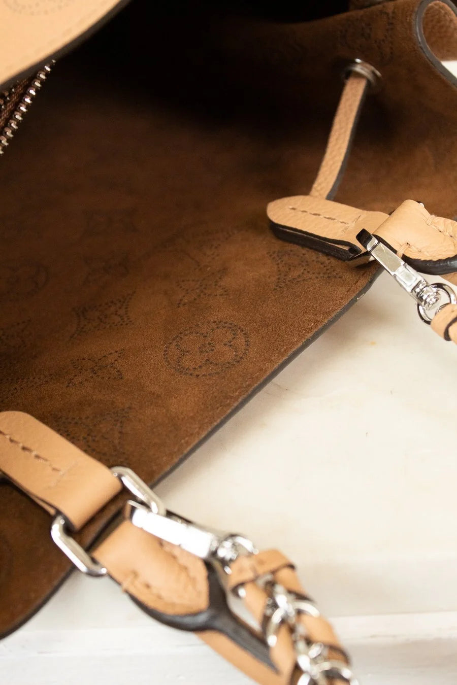 Close-up of a brown leather bag with silver hardware on a white background