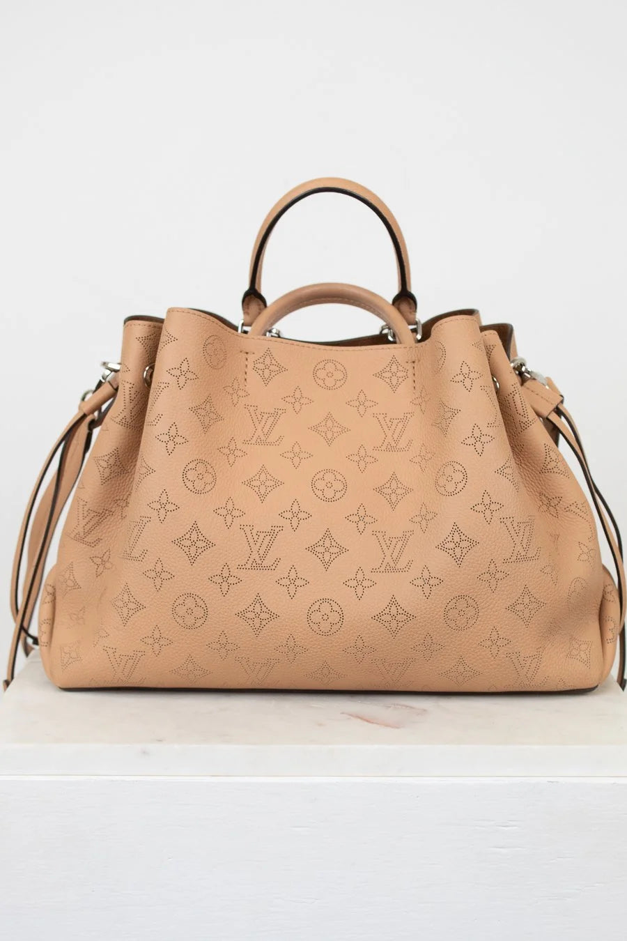 Beige handbag with monogram pattern on a white background