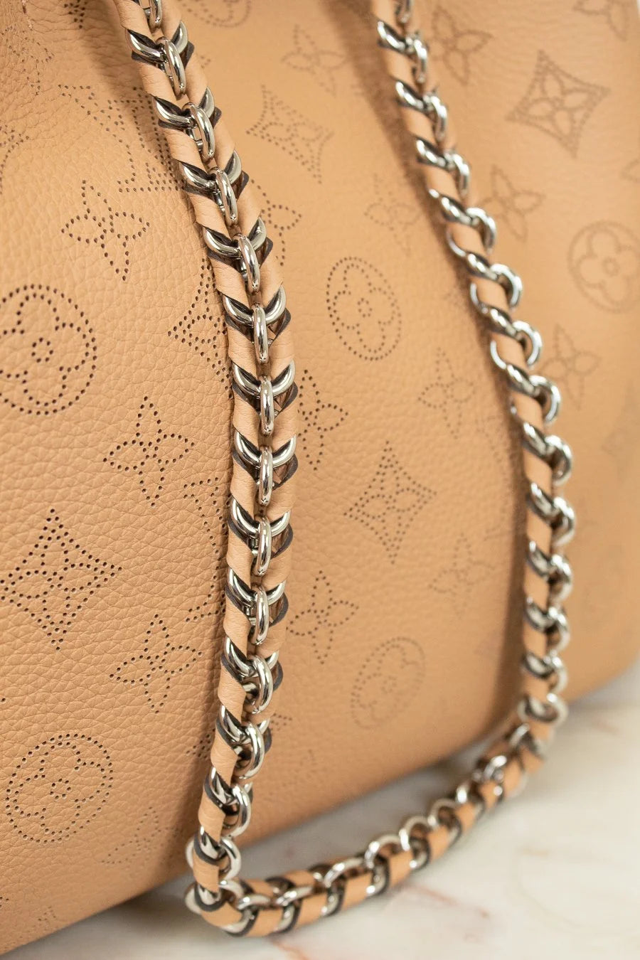 Close-up of a beige handbag with a silver chain detail