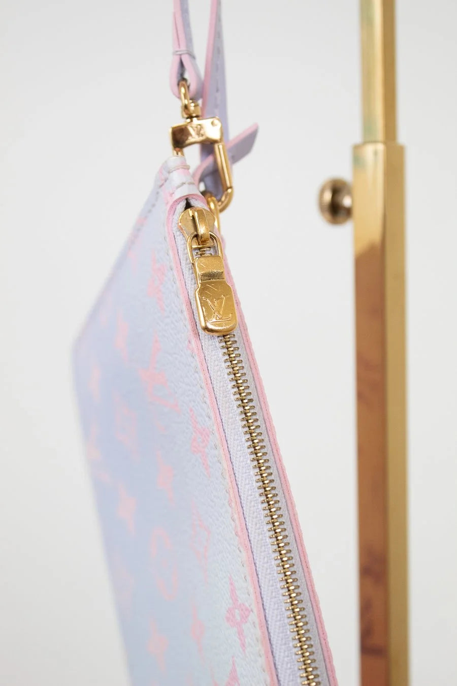 Pouch with gold zipper and monogram pattern on a white background