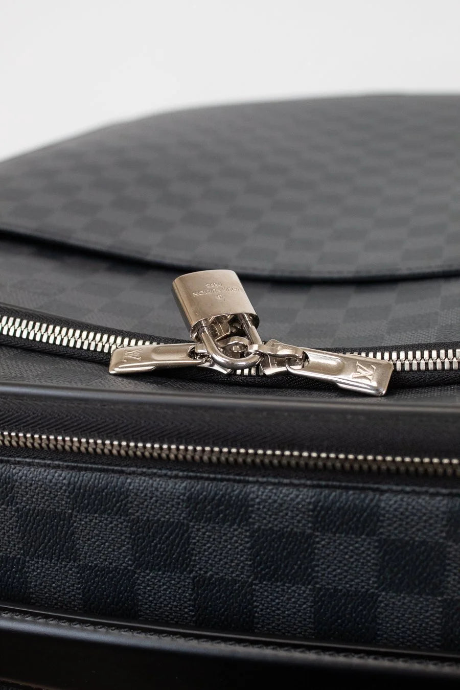 Close-up of a black checkered bag with a silver zipper