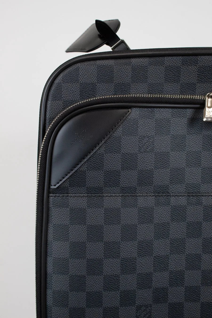 Black checkered suitcase with a silver zipper on a light gray background