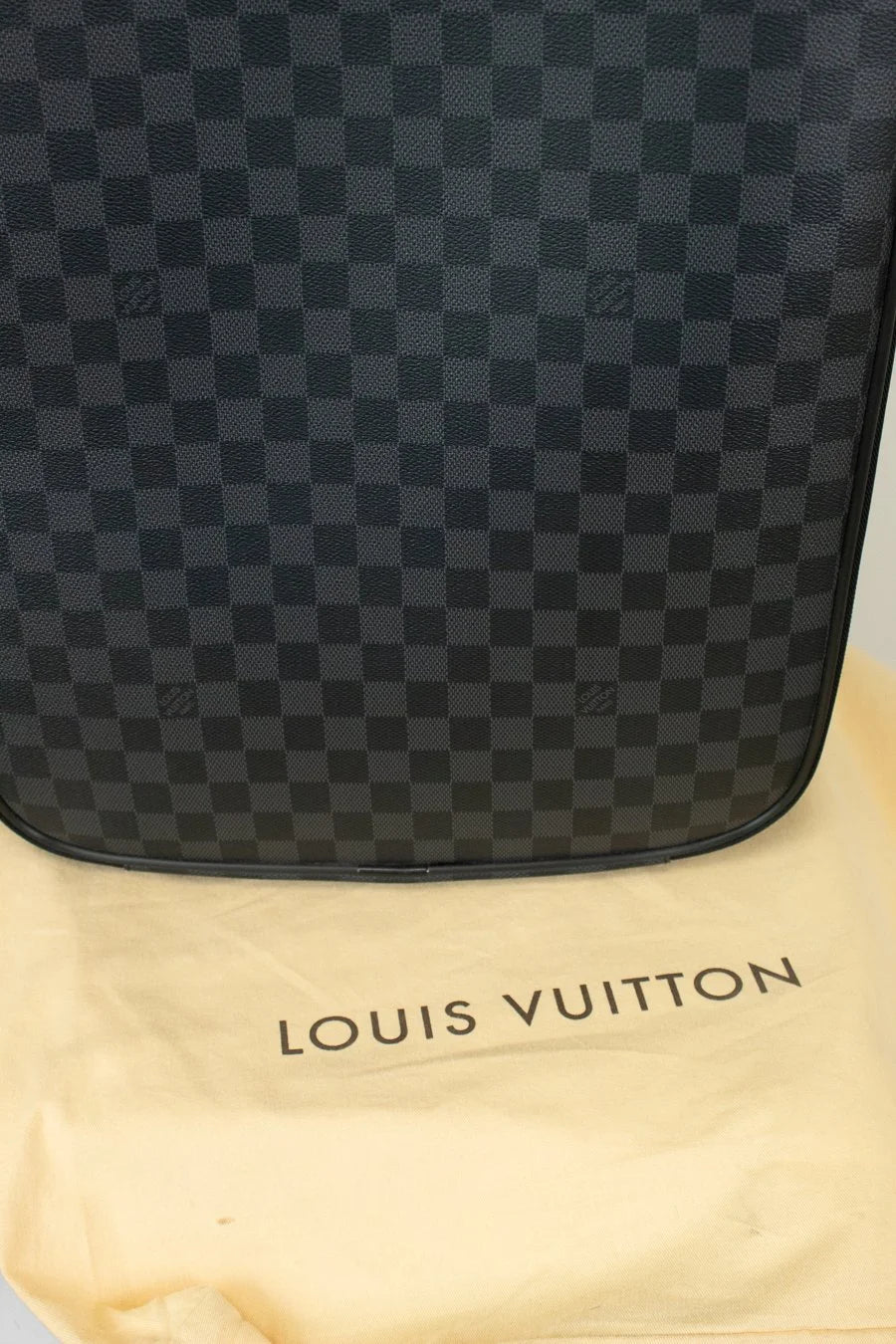 Black checkered Louis Vuitton bag on a beige Louis Vuitton dust bag