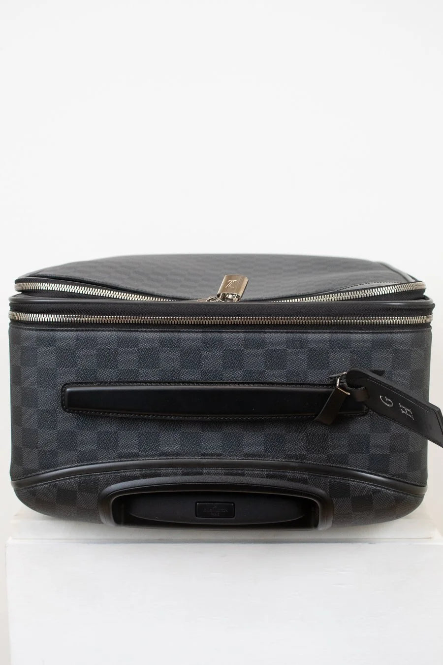 Black checkered suitcase with silver zipper pull on a white background
