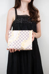 Woman holding a patterned clutch against a plain background