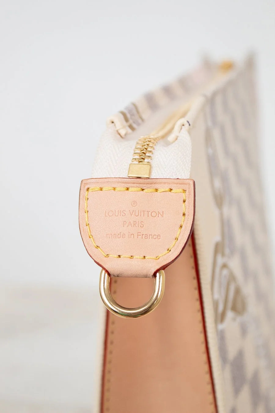 Louis Vuitton keychain loop on a beige handbag with a blurred background