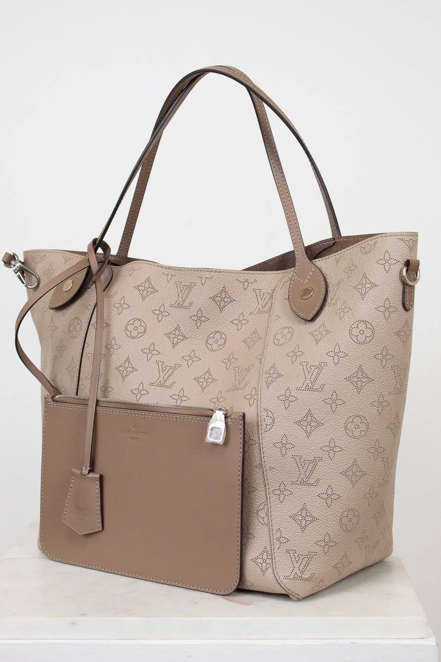 Beige handbag with monogram pattern on a white background