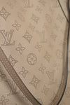 Close-up of a beige leather bag with a pattern of stars and brand logos.