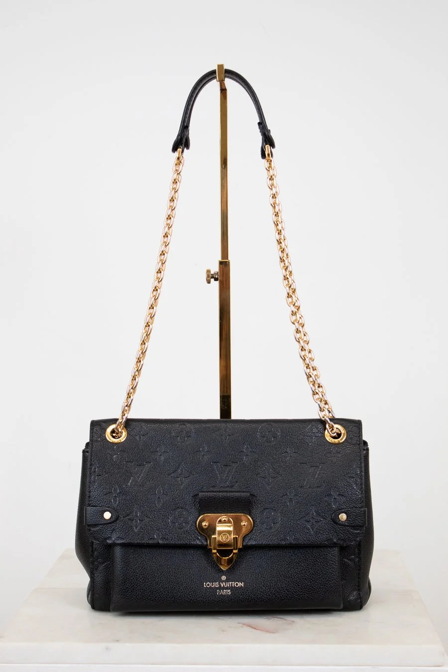 Black handbag with gold chain and hardware on a white background