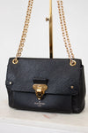 Black handbag with gold chain and clasp on a white surface