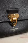 Black Louis Vuitton handbag with gold clasp on a marble surface