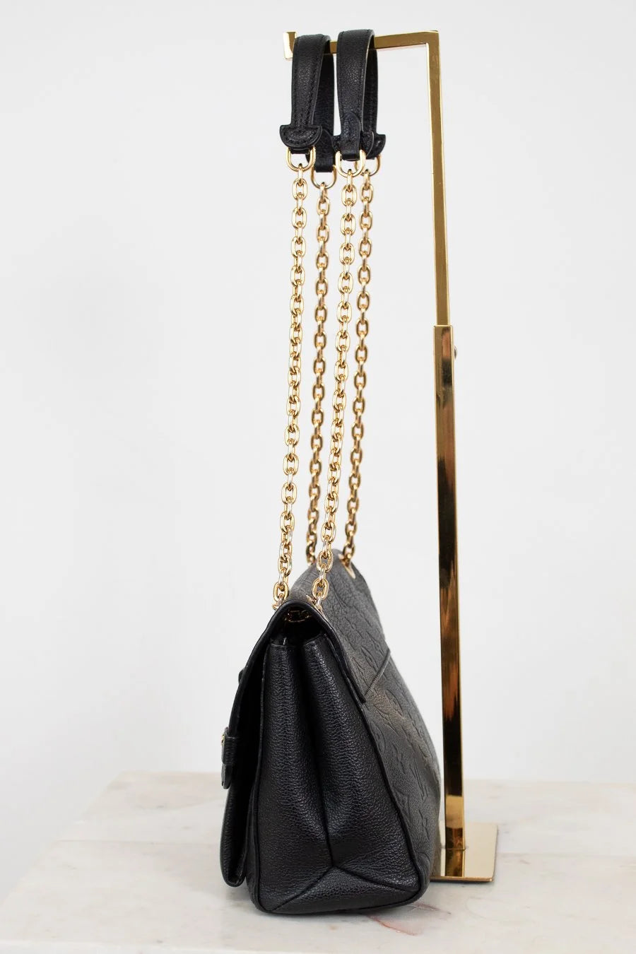 Black handbag with gold chain strap on a white background