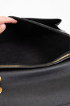 Close-up of a black leather handbag with gold accents.