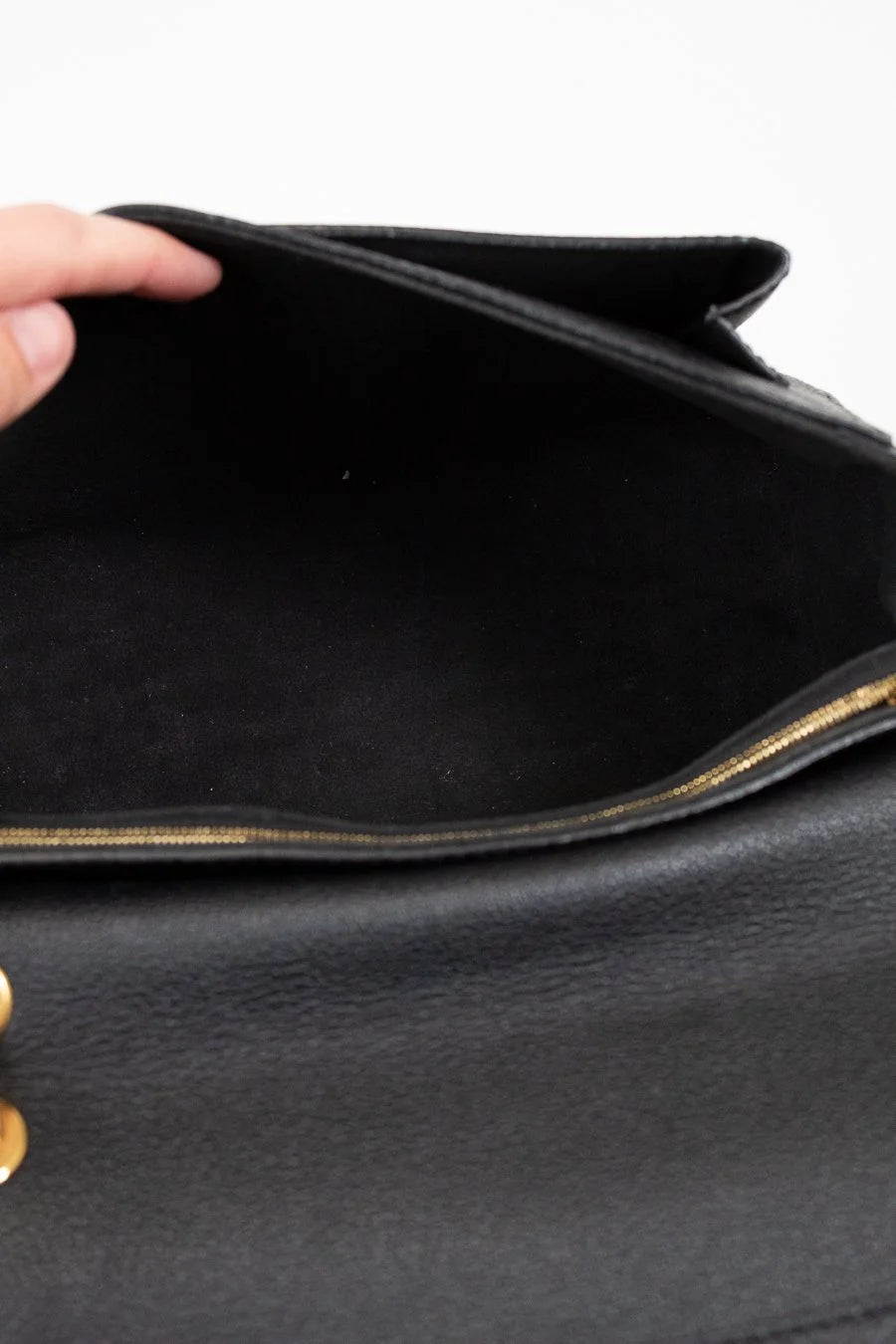 Close-up of a black leather handbag with gold accents.