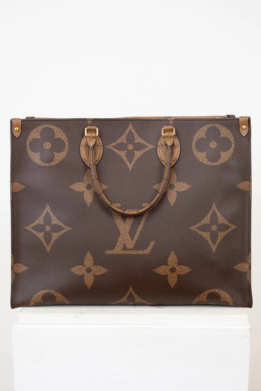 Brown handbag with gold monogram pattern on a white background