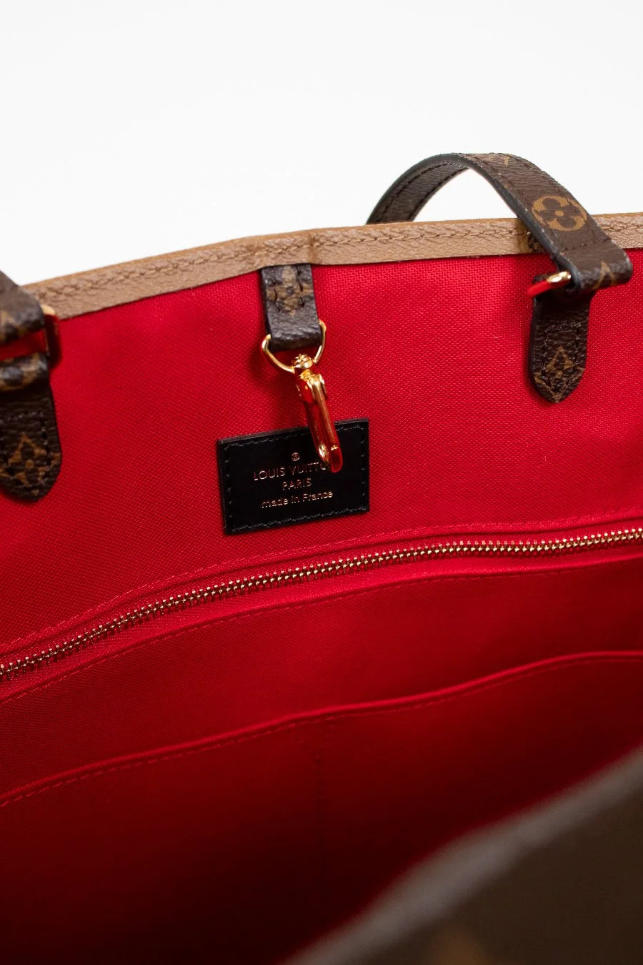 Red suede interior with brown handles and a visible brand tag on a light gray background