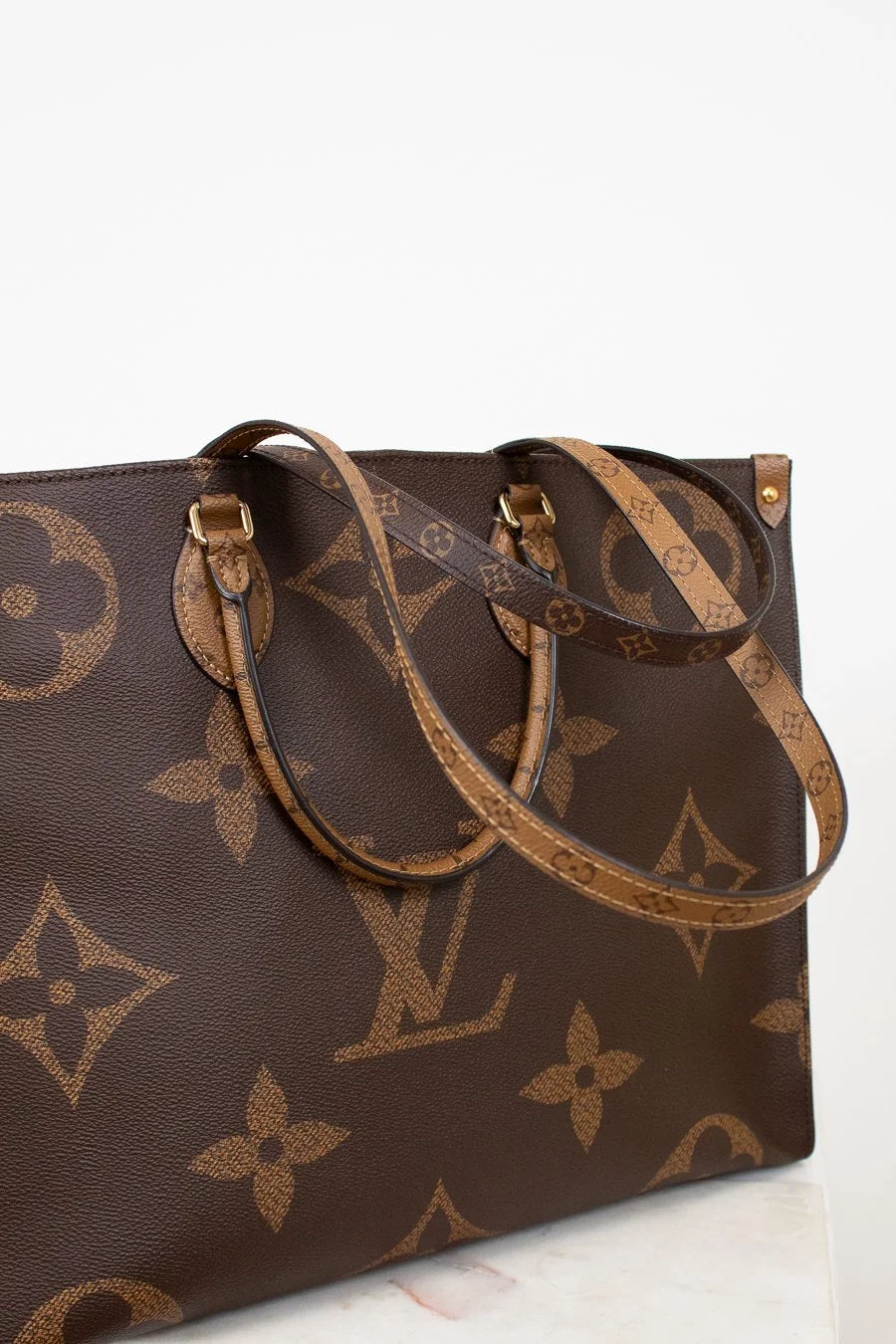 Brown handbag with brand logo pattern on a white background