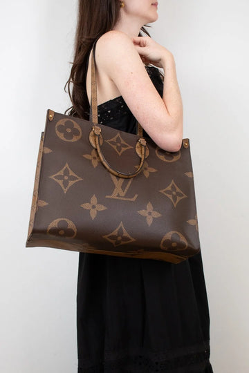 Person holding a brown Louis Vuitton handbag against a white background
