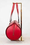 Red handbag with black piping accents on a white background