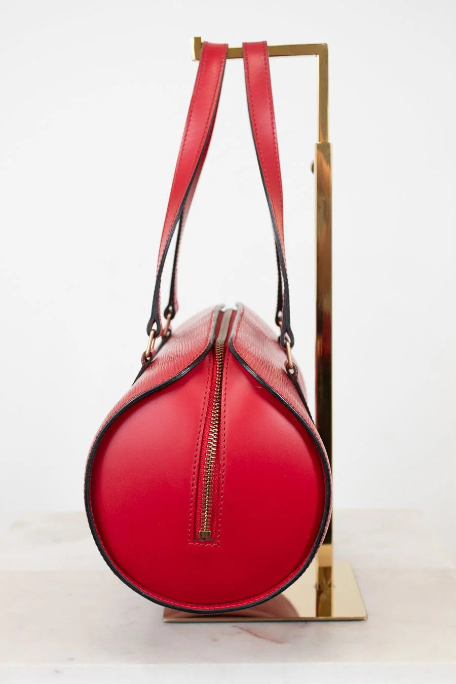 Red handbag with black piping accents on a white background