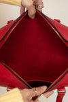 Red handbag held open by a person's hands, showing the interior.