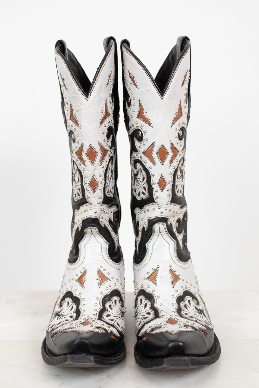 A pair of white western cowboy boots with black and brown leather details, shown from the front against a plain white background.