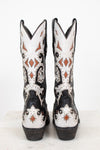 A pair of western cowboy boots shown from the back, featuring a black and white leather base with intricate brown and black leather detailing and silver studs.