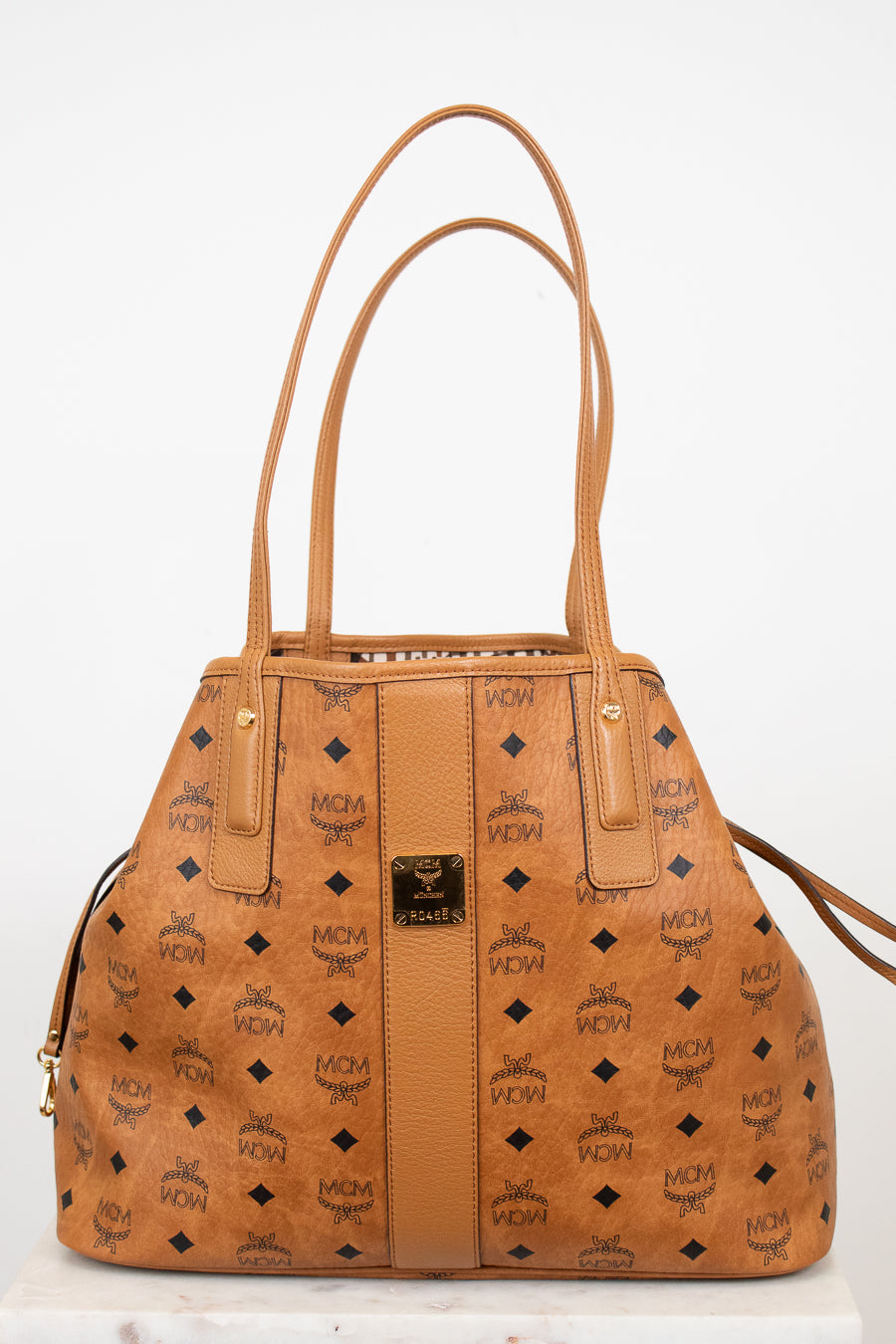 Tan handbag with brand logo on a white background