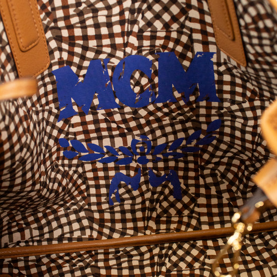 Close-up of an abstract checkered design on bag with 'MCM' branding in blue text.