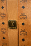 Close-up of a brown leather bag with MCM logo and branding.