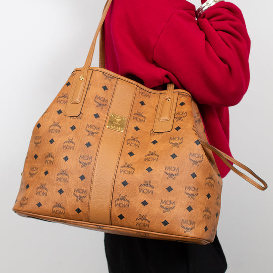 Person holding a brown patterned handbag against a plain background