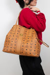 Person holding a brown patterned handbag against a plain background
