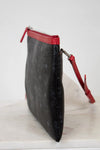 Black clutch bag with red accents on a white surface