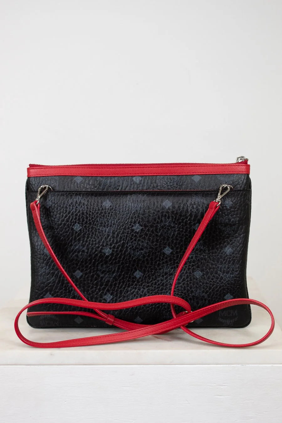 Black textured handbag with red accents on a white background