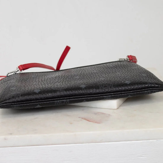 Black textured pouch with red zippers on a white surface
