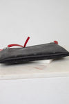 Black textured pouch with red zippers on a white surface