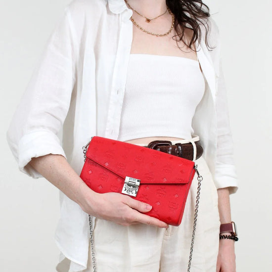 Person holding a red clutch bag against a white background