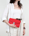 Person holding a red clutch bag against a white background