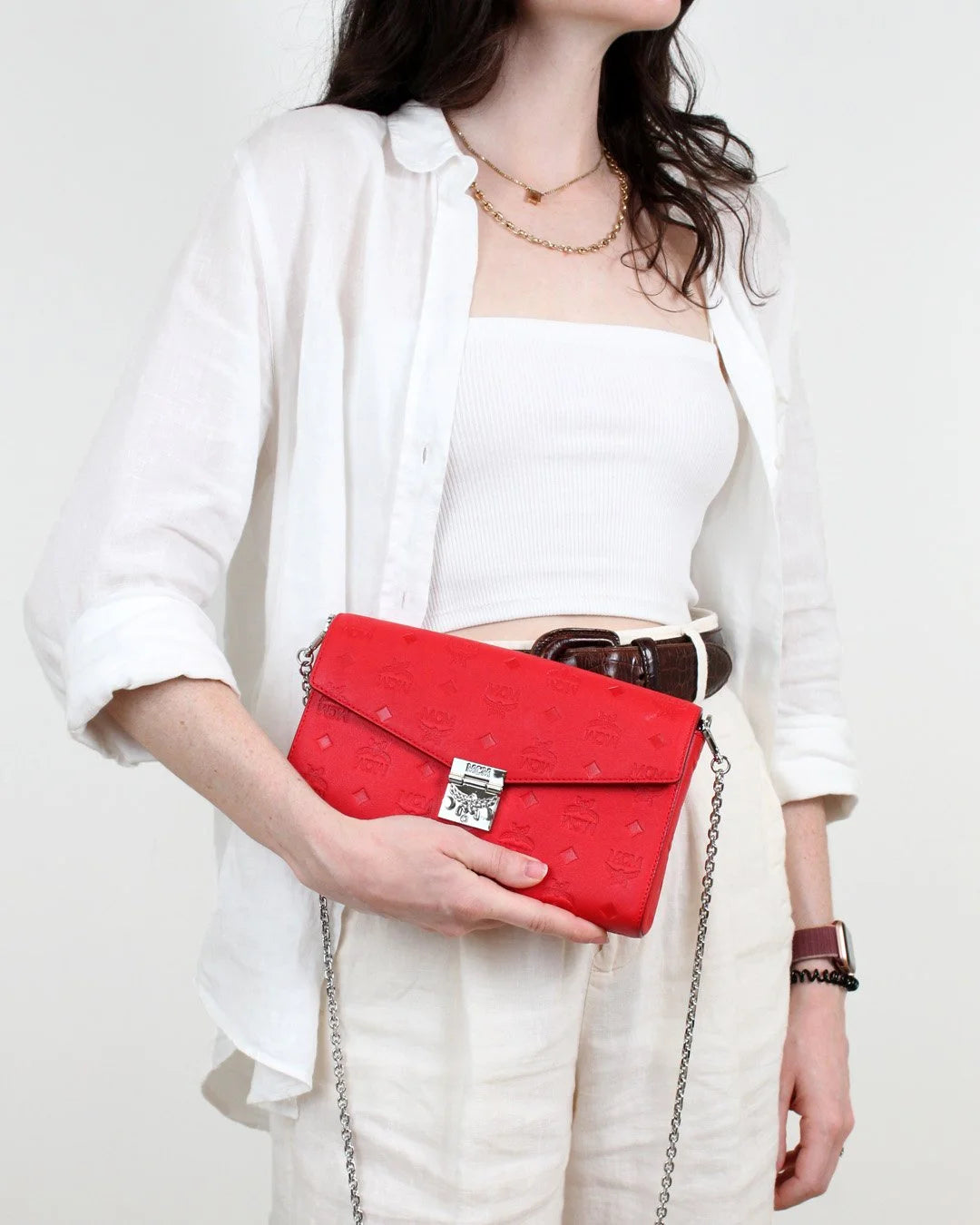 Person holding a red clutch bag against a white background